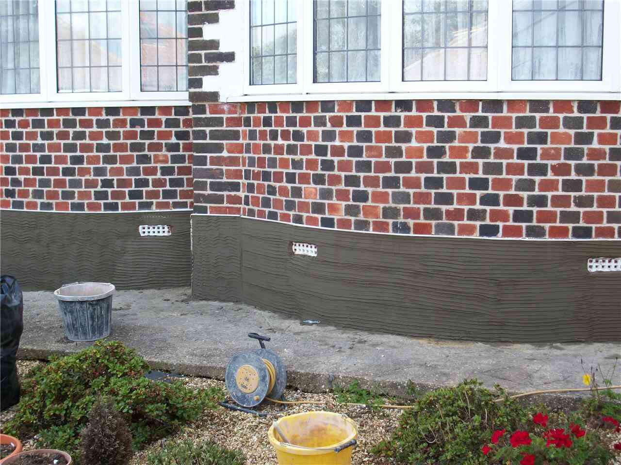 Rendered wall with finished brick plinth